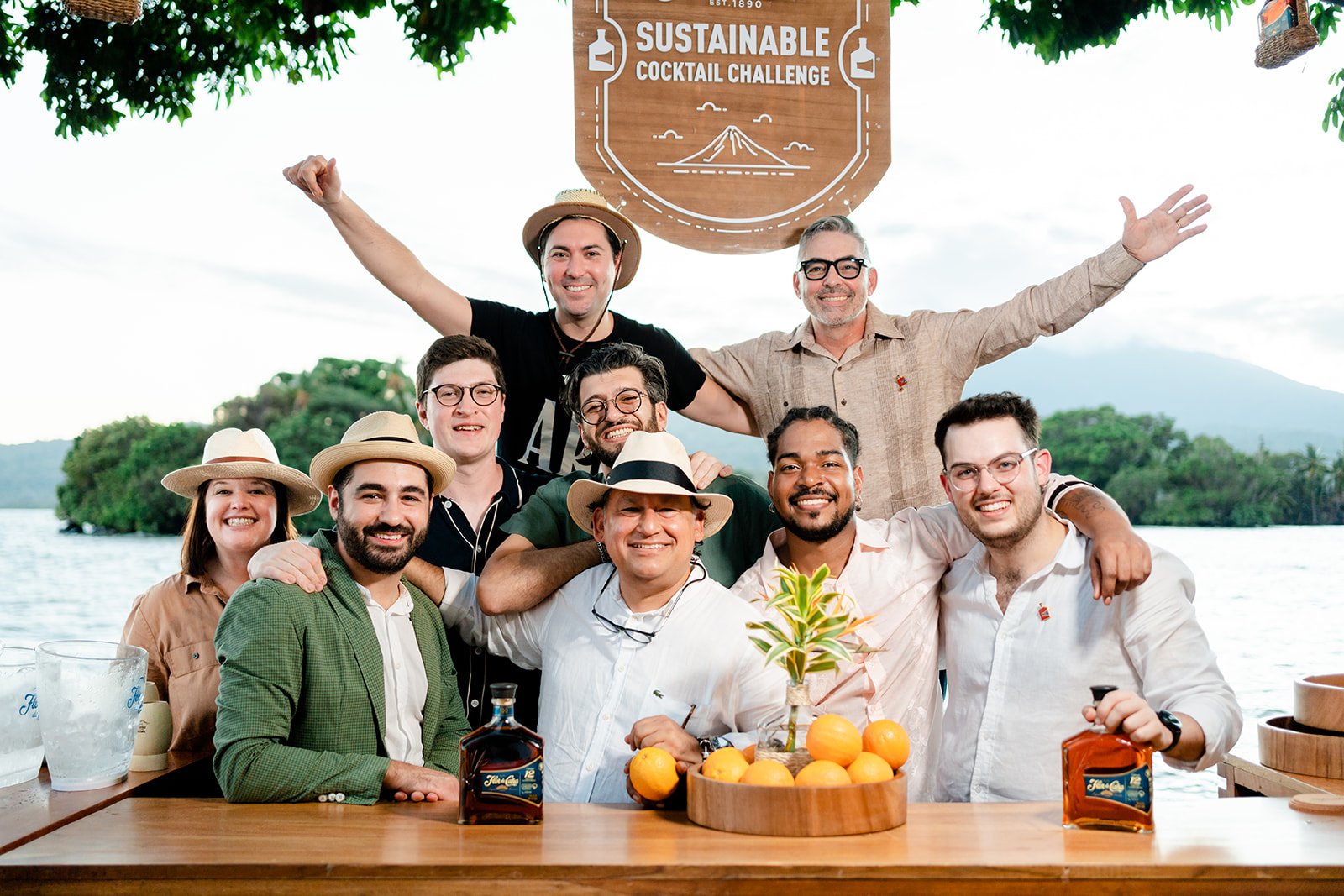 Group of smiling people with bottles of rum and island background at Flor de Cana Sustainable Cocktail Challenge