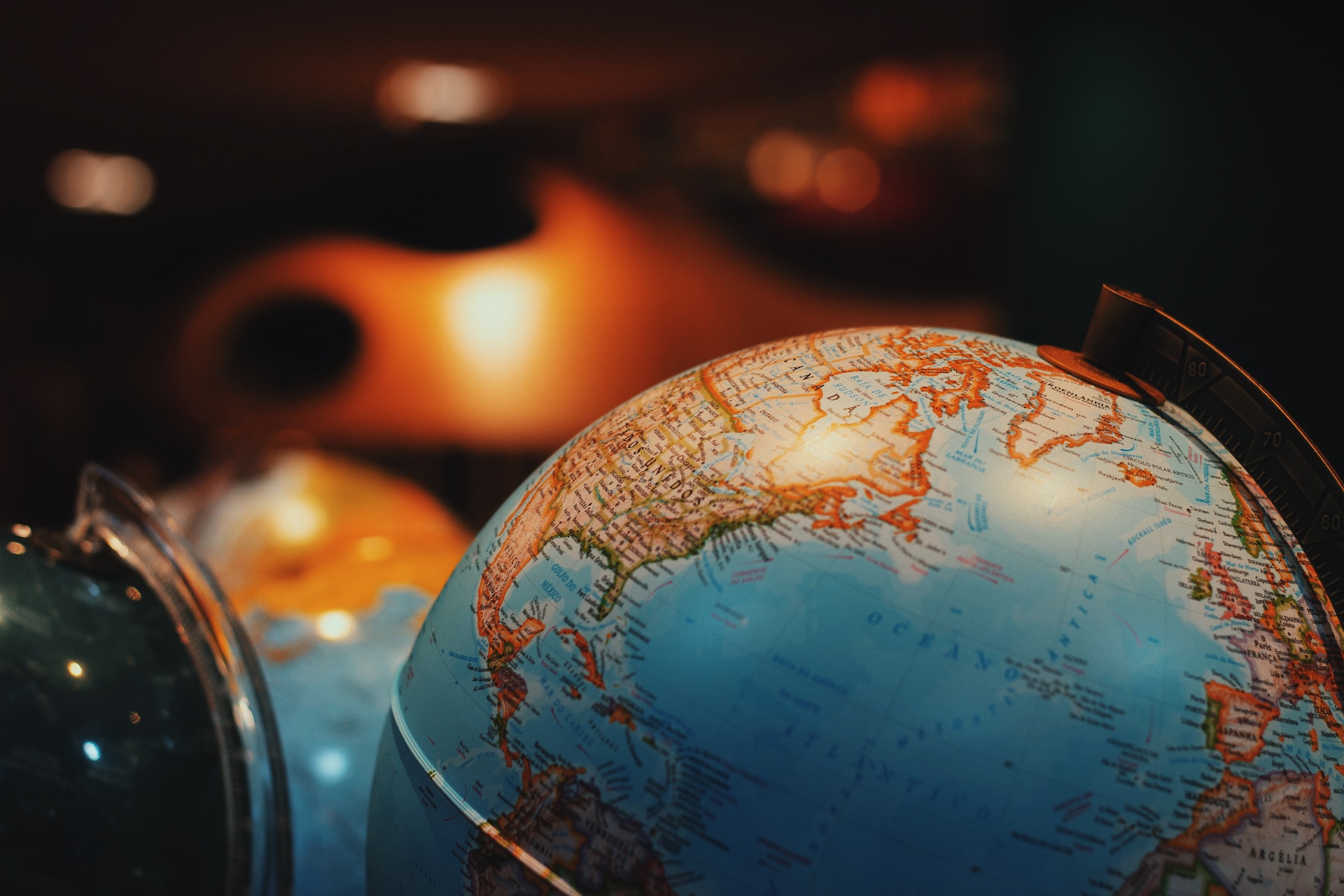 Stock image of globe in foreground with dark, warm-toned room out of focus in the background