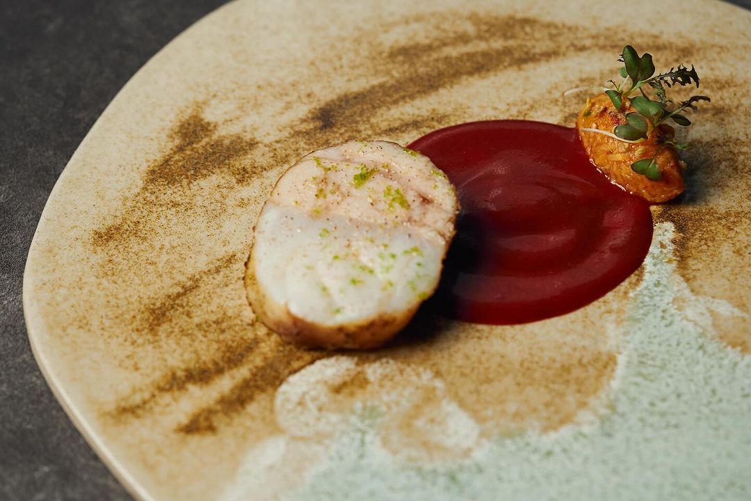 Piece of monkfish with sauce on beige plate