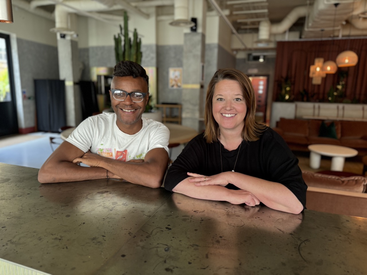 Deano Moncrieffe and Juliane Caillouette Noble sitting at table with arms folded