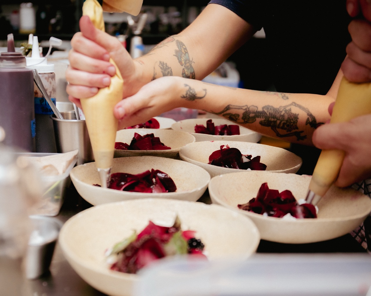 A chef piping sauce onto a beetroot dish at venn canteen