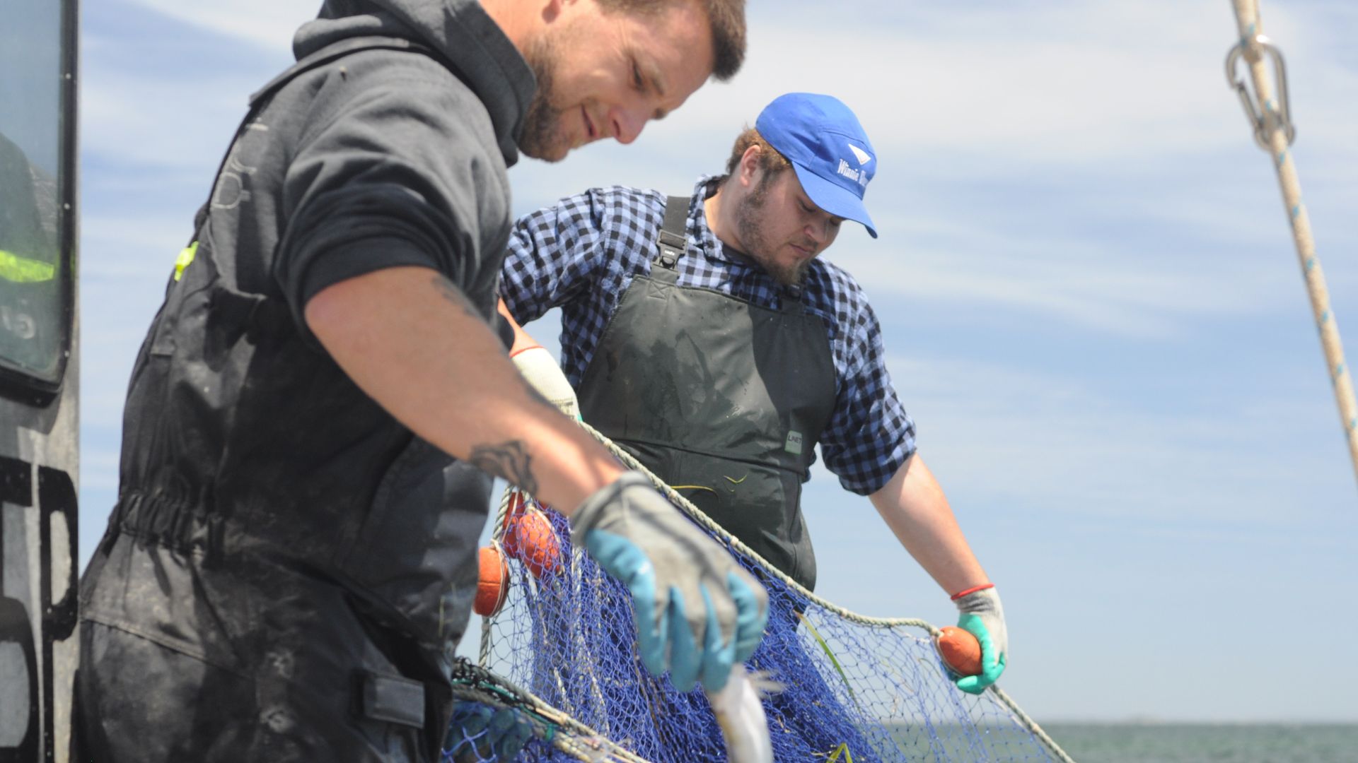Two fishermen on a boat holding a net