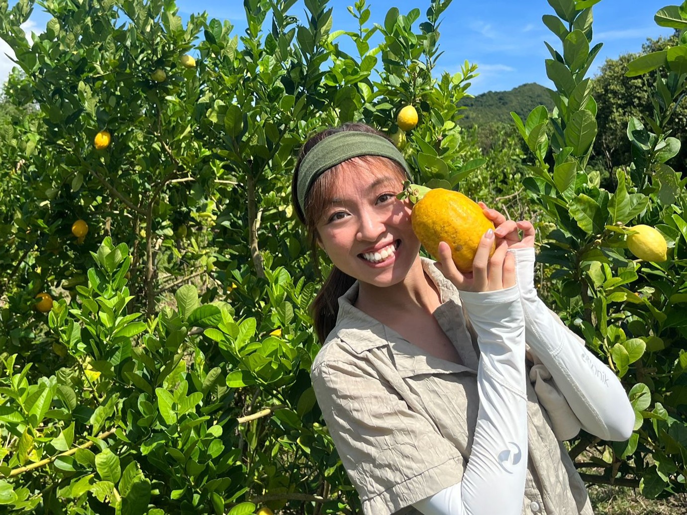Photo of Clare Pang holding a lemon in a sunny garden
