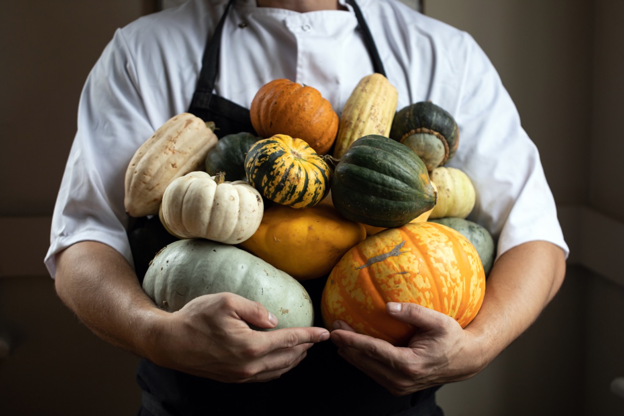 Chef holding pumpkins and squashes of all different sizes and colours