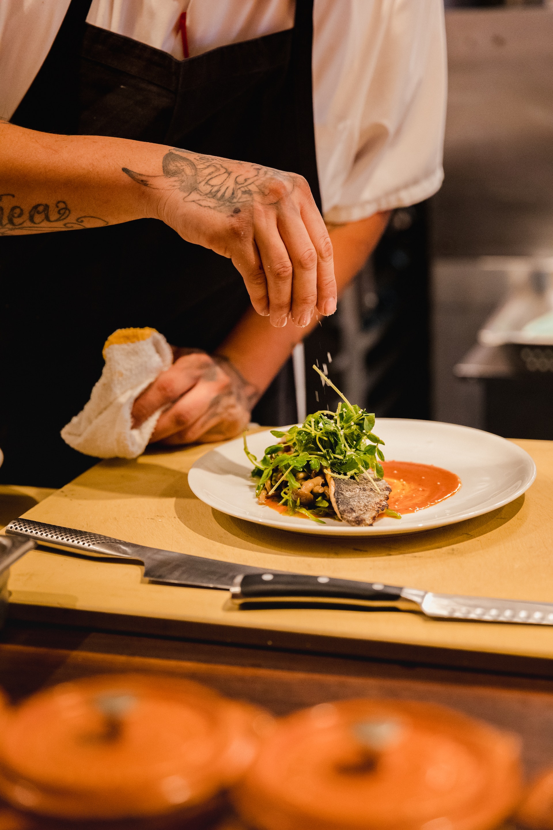 Chef's hand garnishing finished dish