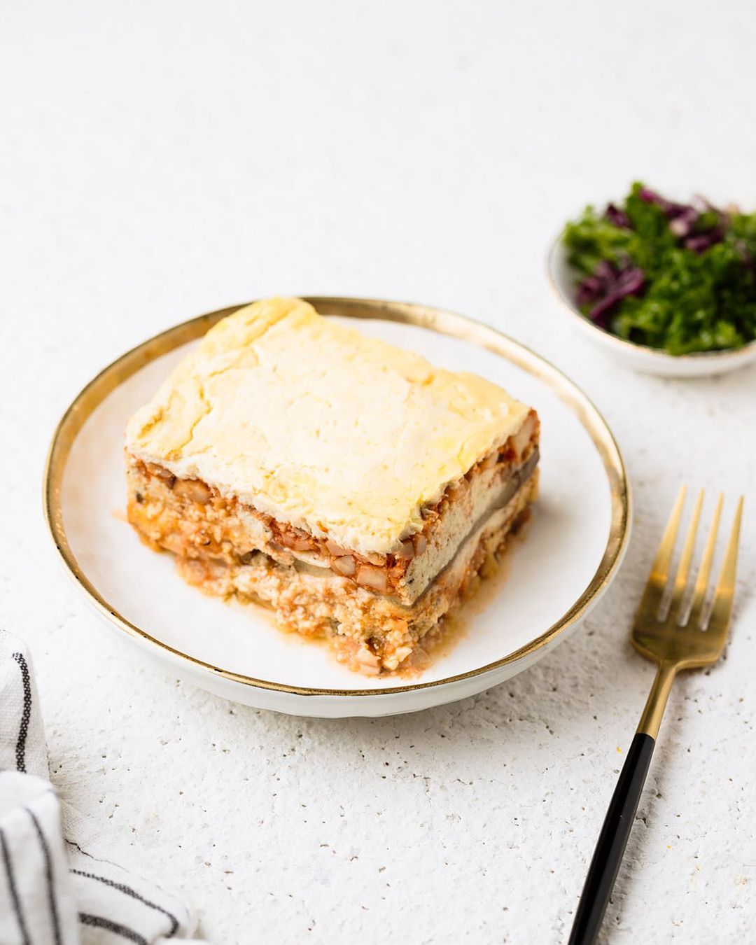 Plate of stacked food with fork and side salad
