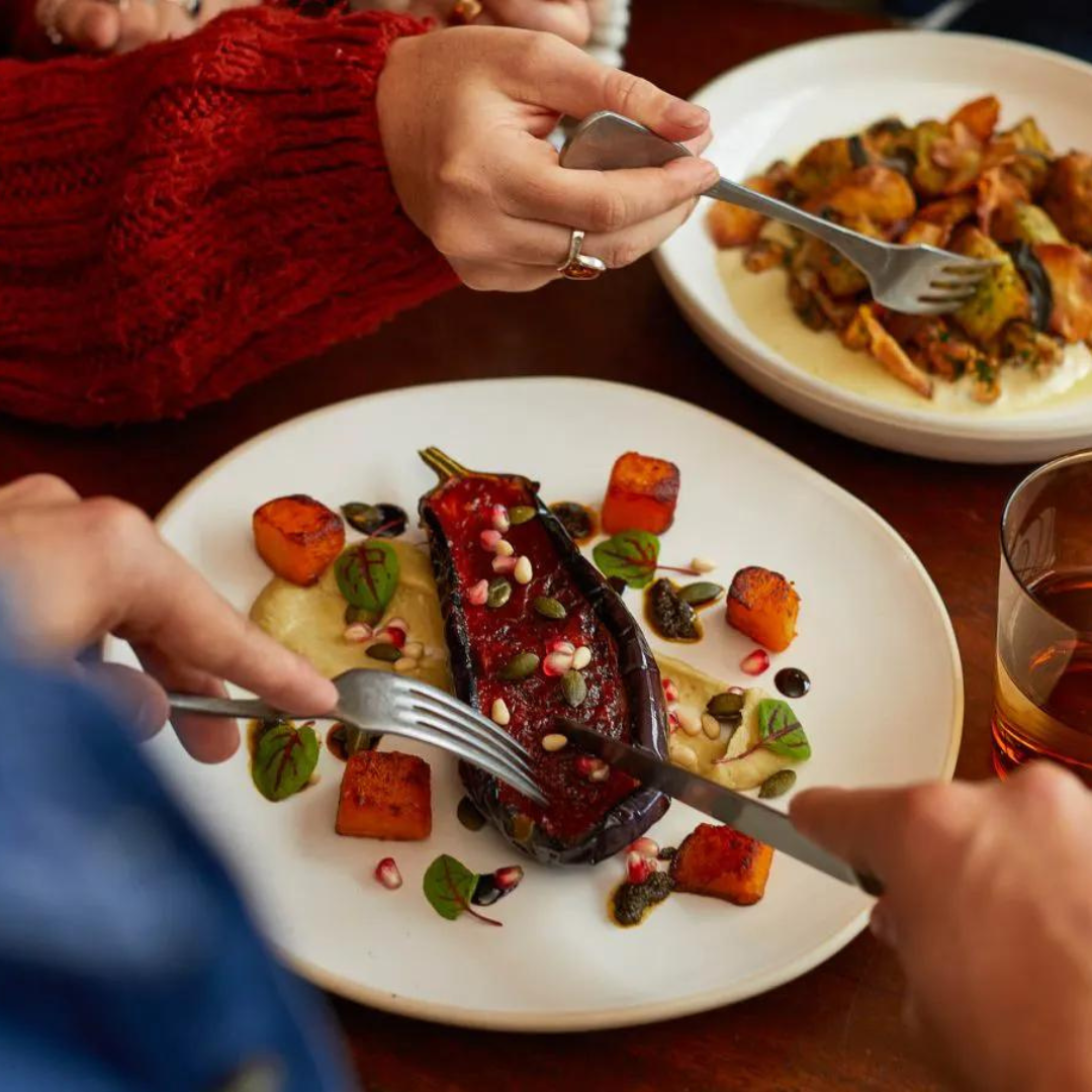 Person eating aubergine dish Heartwood Collection