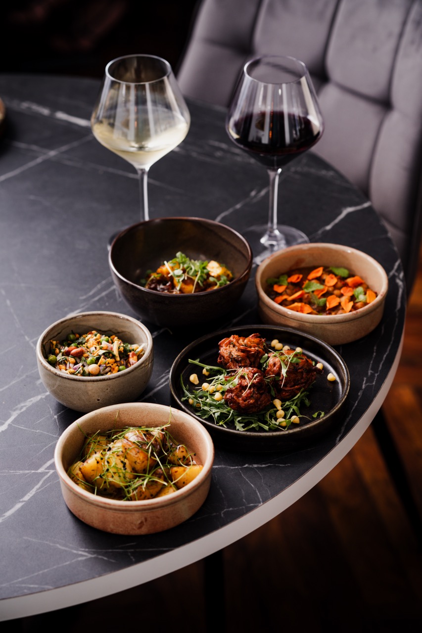 Selection of Lavang dishes on dark table with two glasses of wine