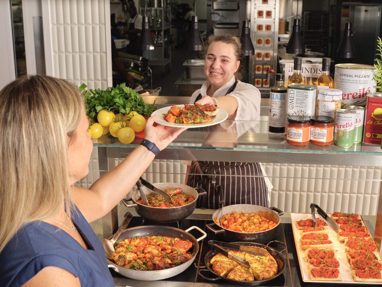 Member of staff at Restaurant Associates handing a customer a plate of food over counter