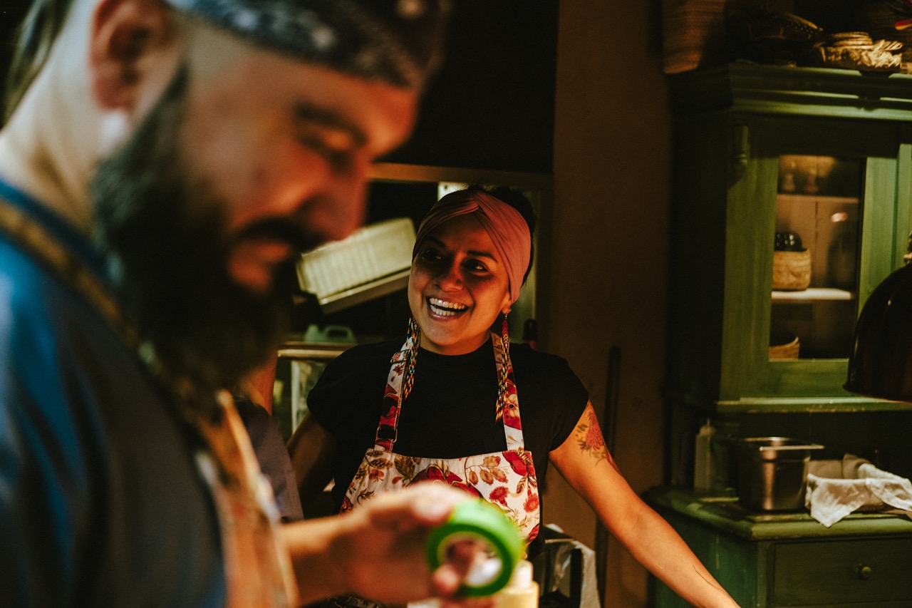 Chef Adriana Cavita in kitchen smiling at man blurred in foreground