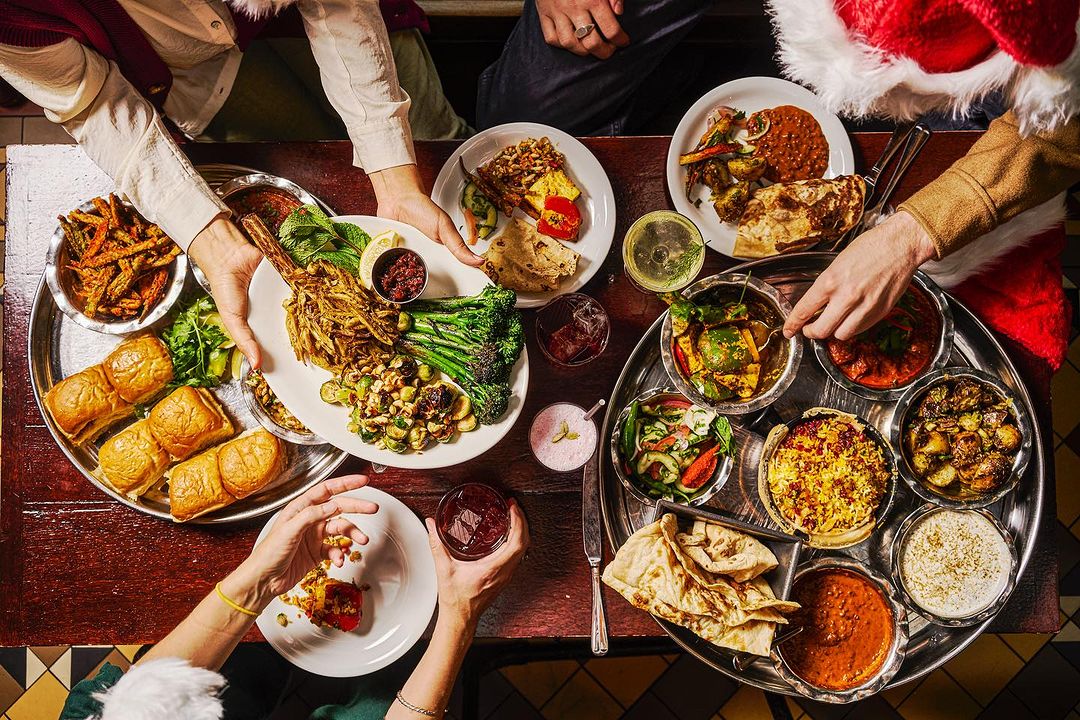 Overhead shot of people sharing table of food at Dishoom