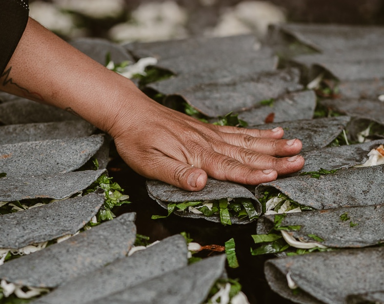 A hand pressing down on folded tortillas