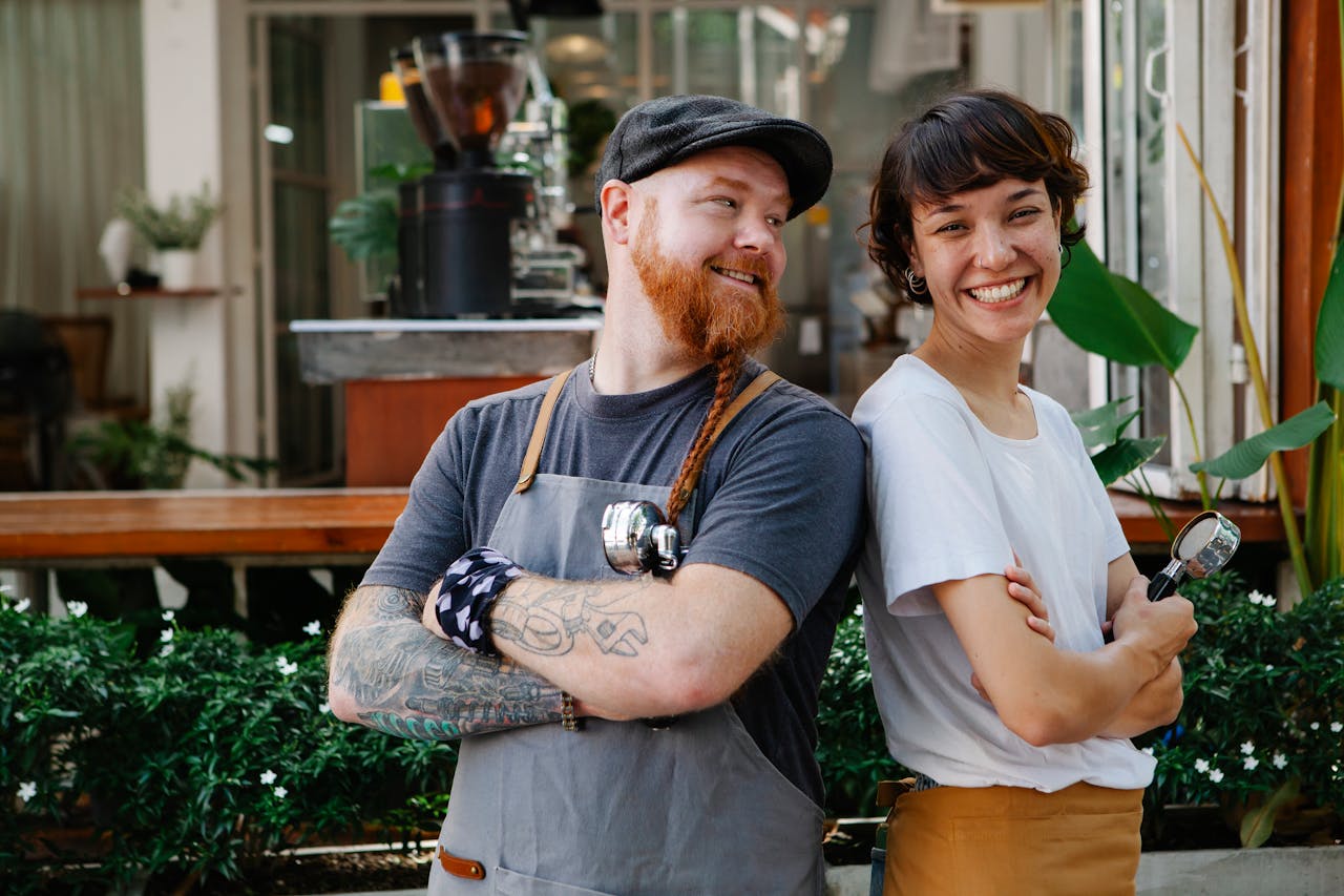 Two restaurant staff standing back to back and smiling