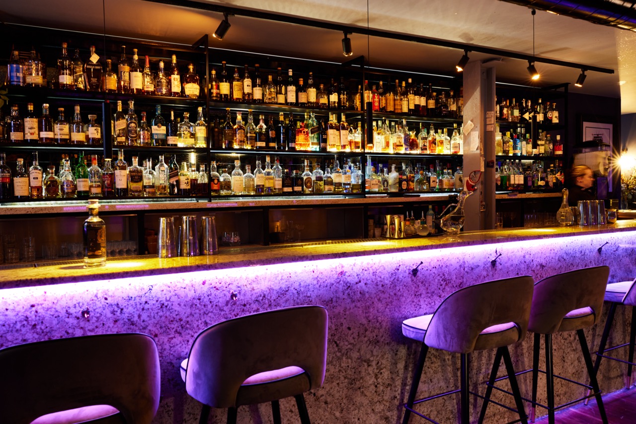 The bar counter at Eve Bar lit with purple under-lighting