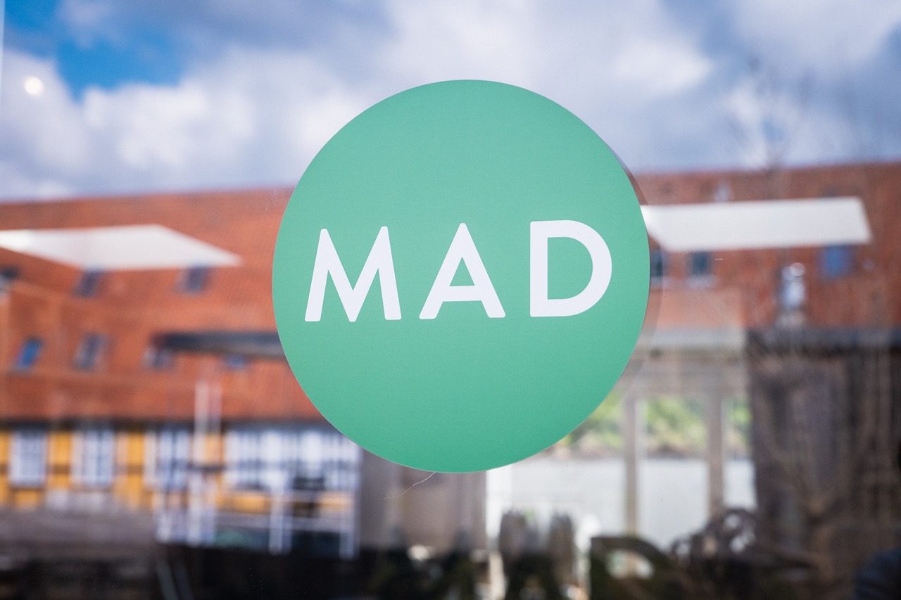 MAD Academy logo against a background of a building exterior