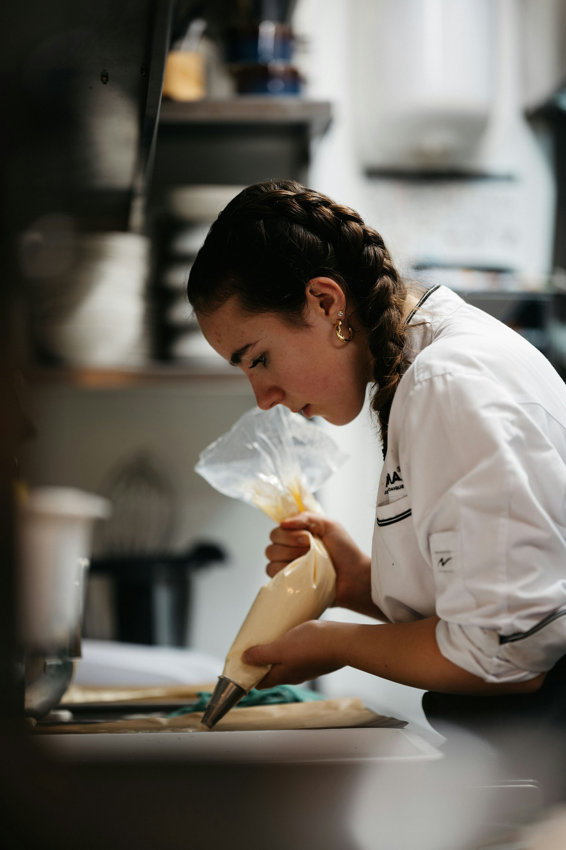 A chef with braided hair piping pastry cream