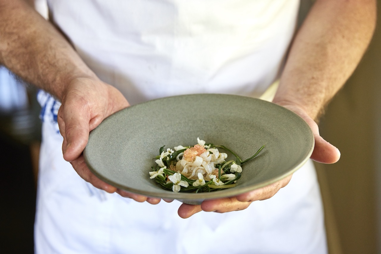 Hands hold a dish of southern calamari at Brae restaurant