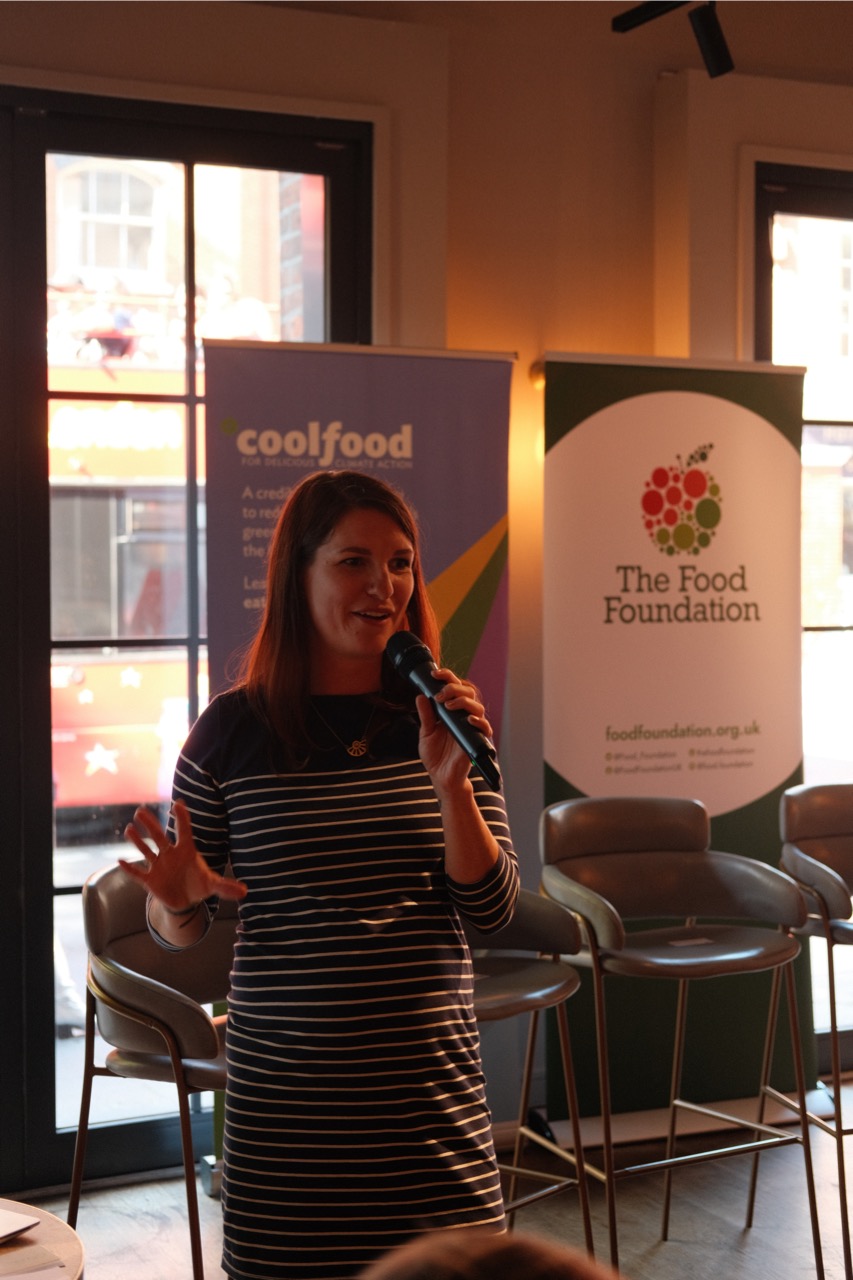 Chloe MacKean from the Food Foundation speaking into a microphone at the Rethinking the Menu event