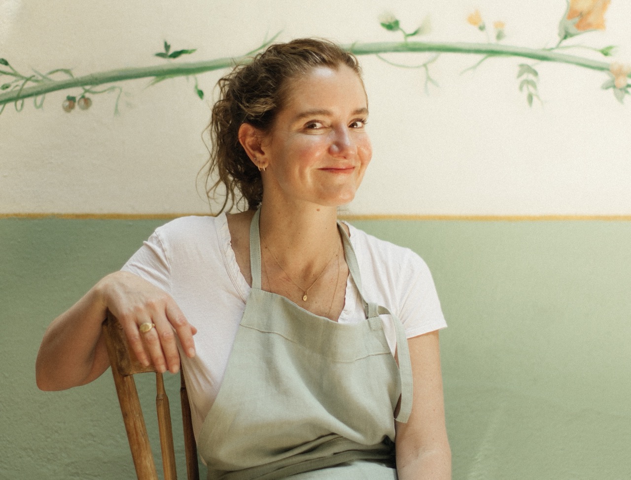 Chef Elena Reygadas from Rosetta sitting in chair wearing apron and smiling at camera