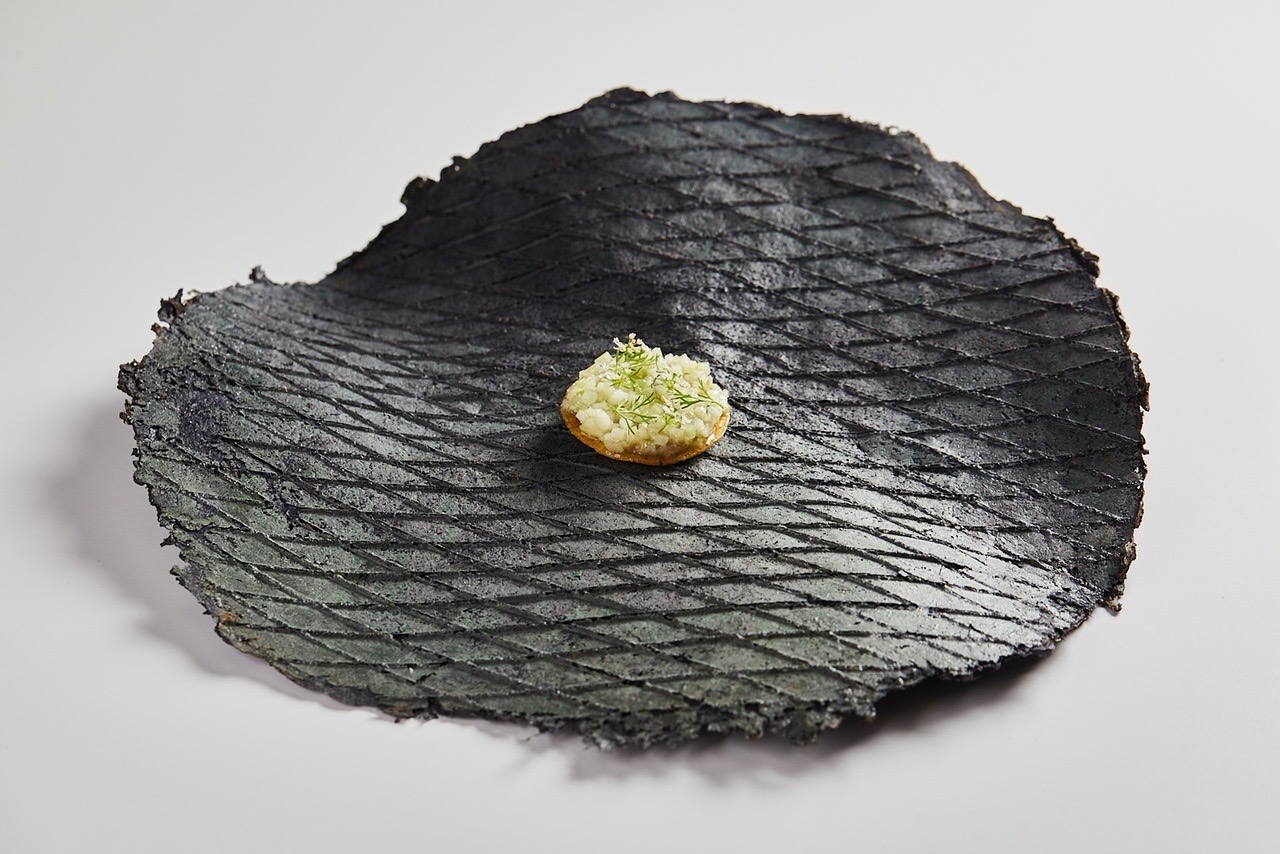 A striking black plate with a small bite of food at K'U'UK restaurante
