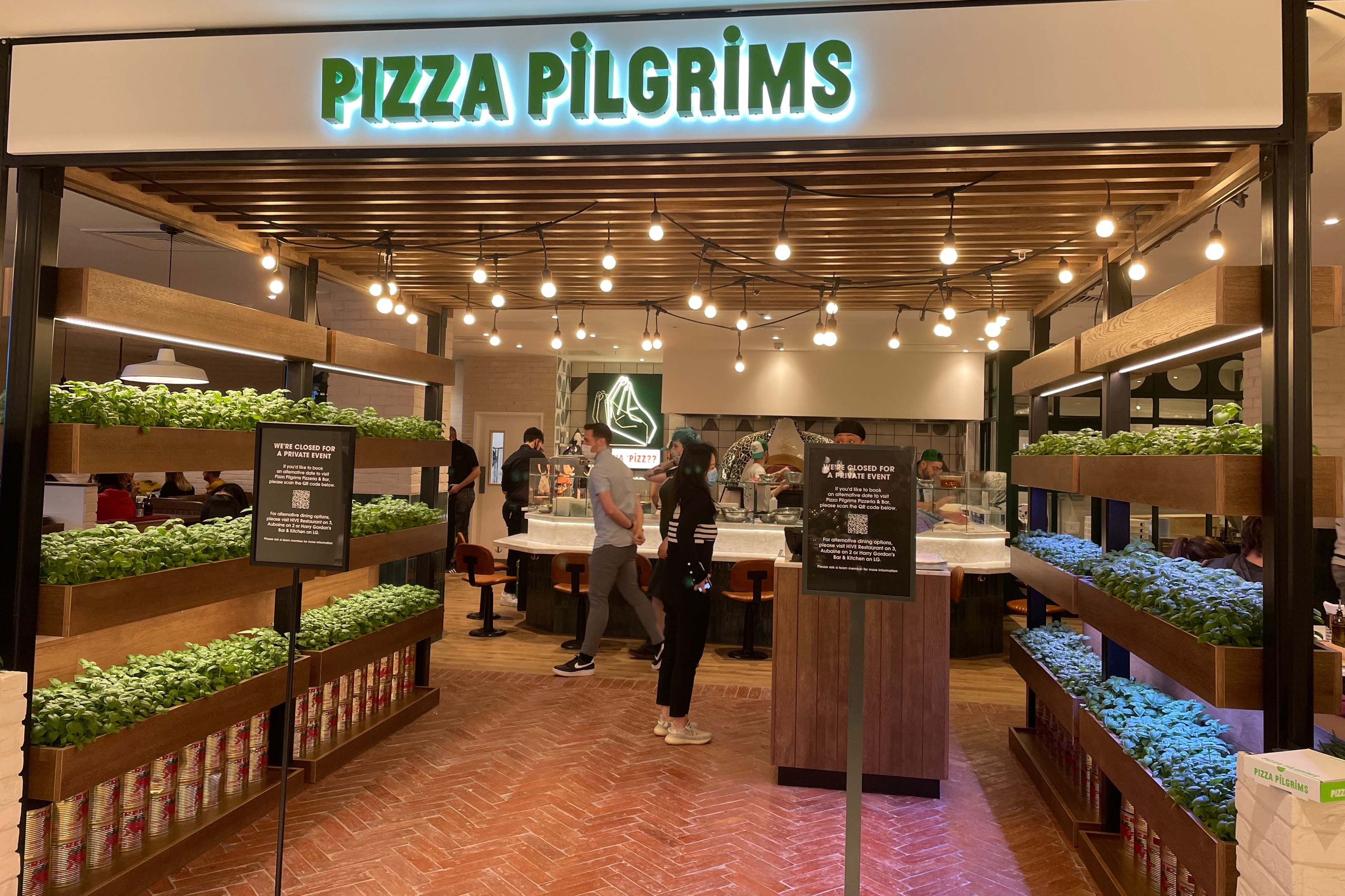 Pizza Pilgrims interior shot with two customers and pots of basil