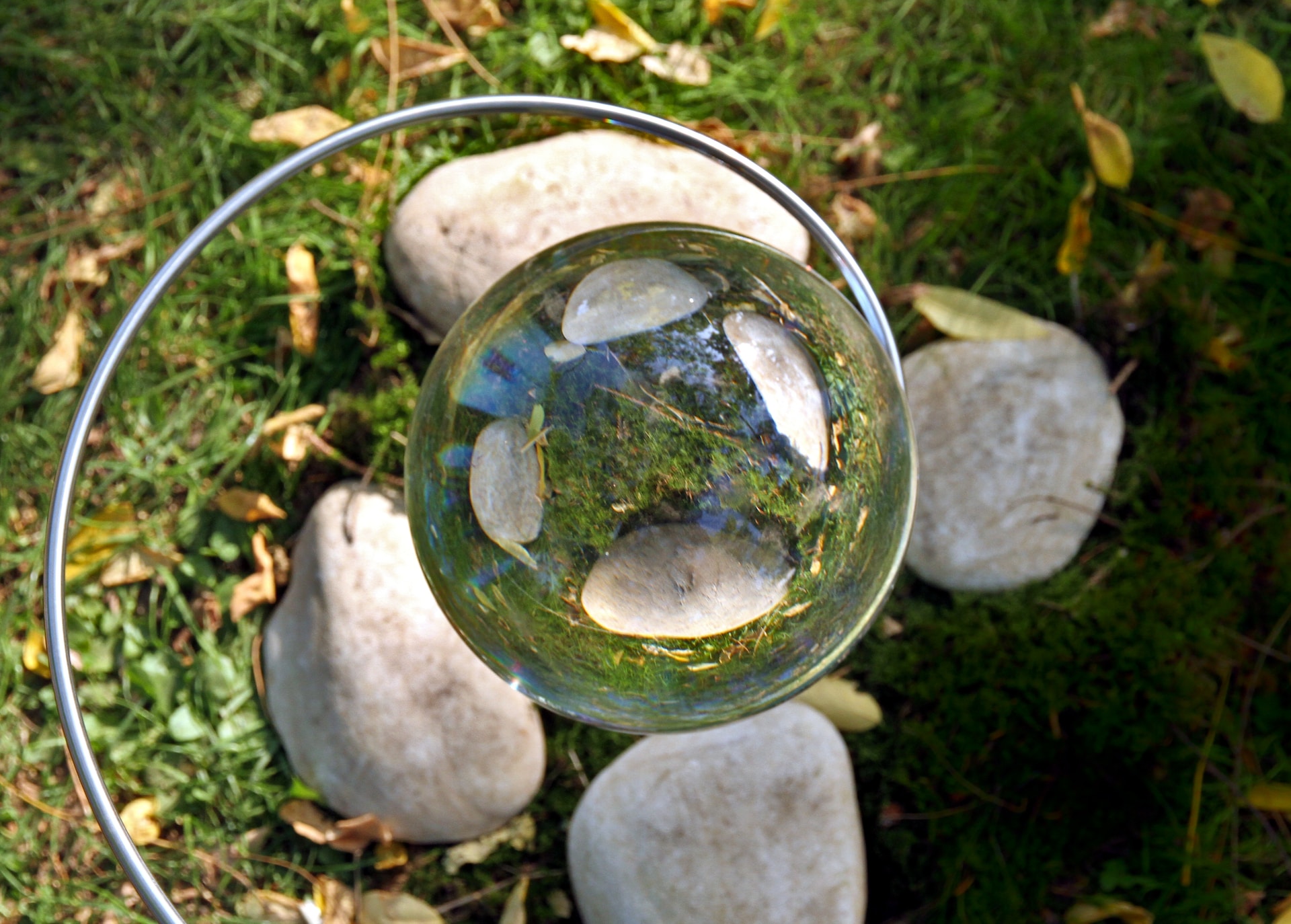 Spiral with glass marble held over four grey rocks on grass