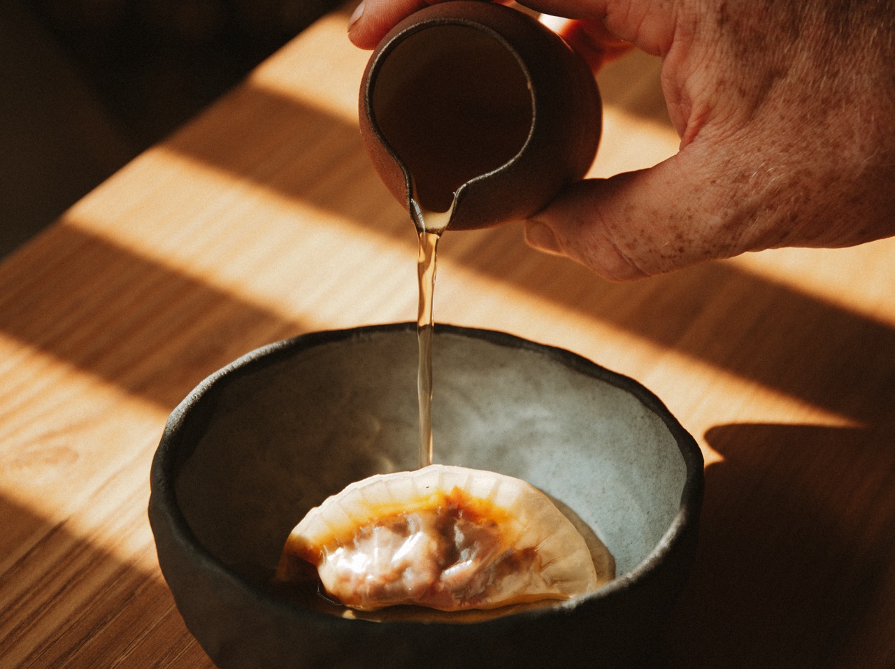 Hand pouring sauce over a dumpling at Wild Shropshire