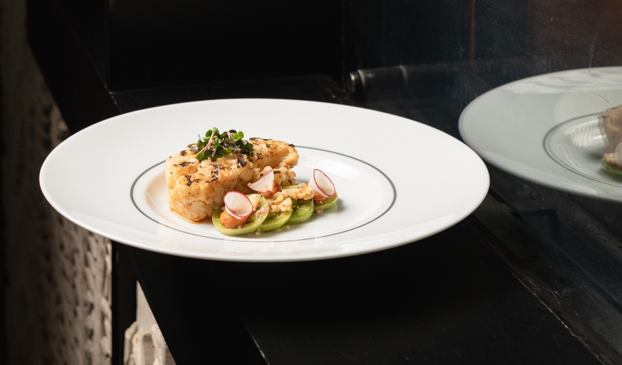 A white plate of food on a dark surface against a black background