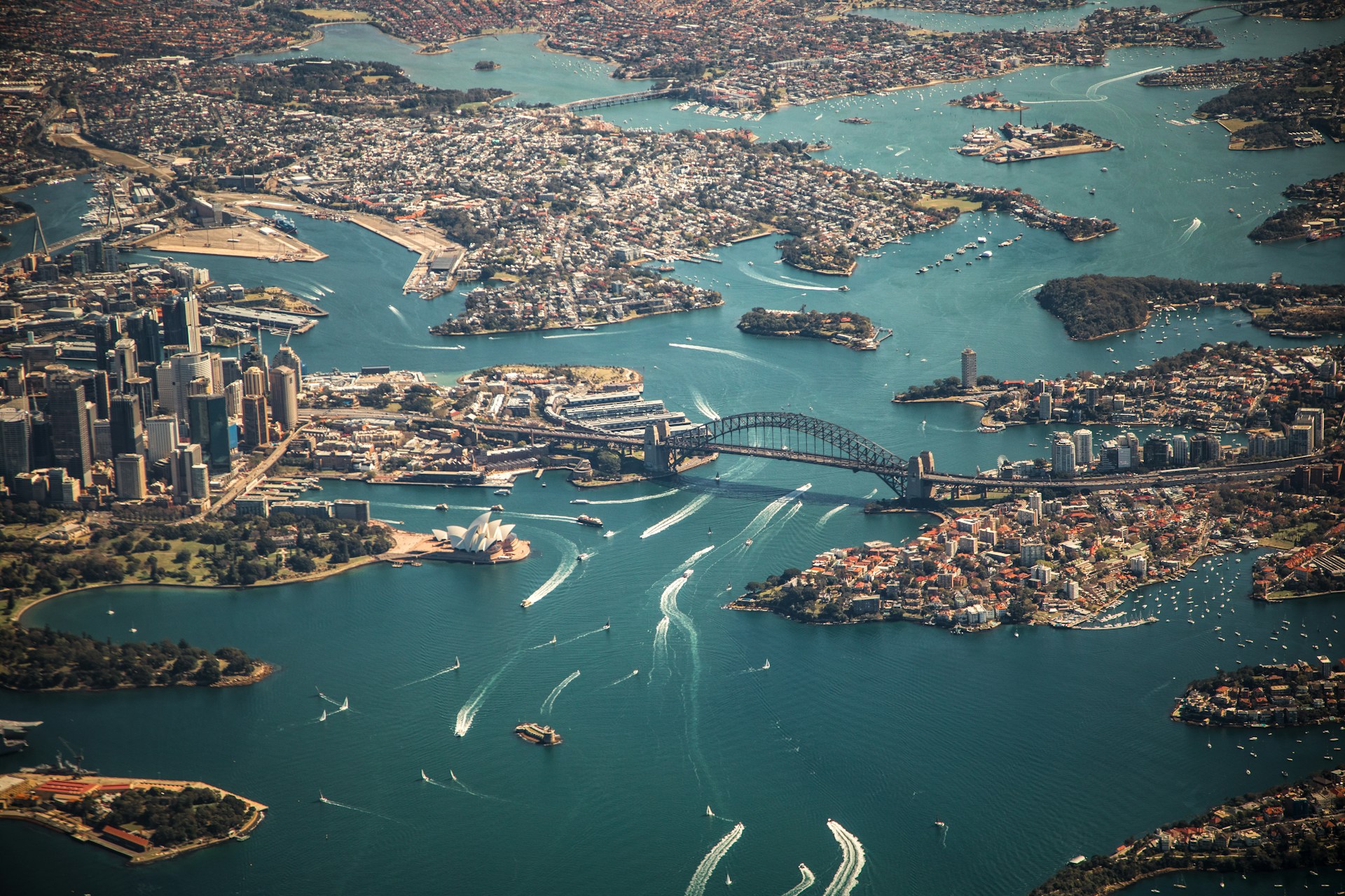 Aerial shot of Sydney city and harbour with Opera House, bridge and boats
