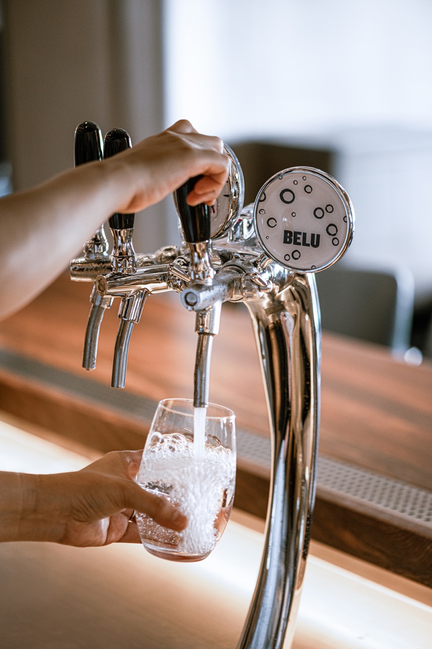 Hand pouring Belu filtered water from a tap