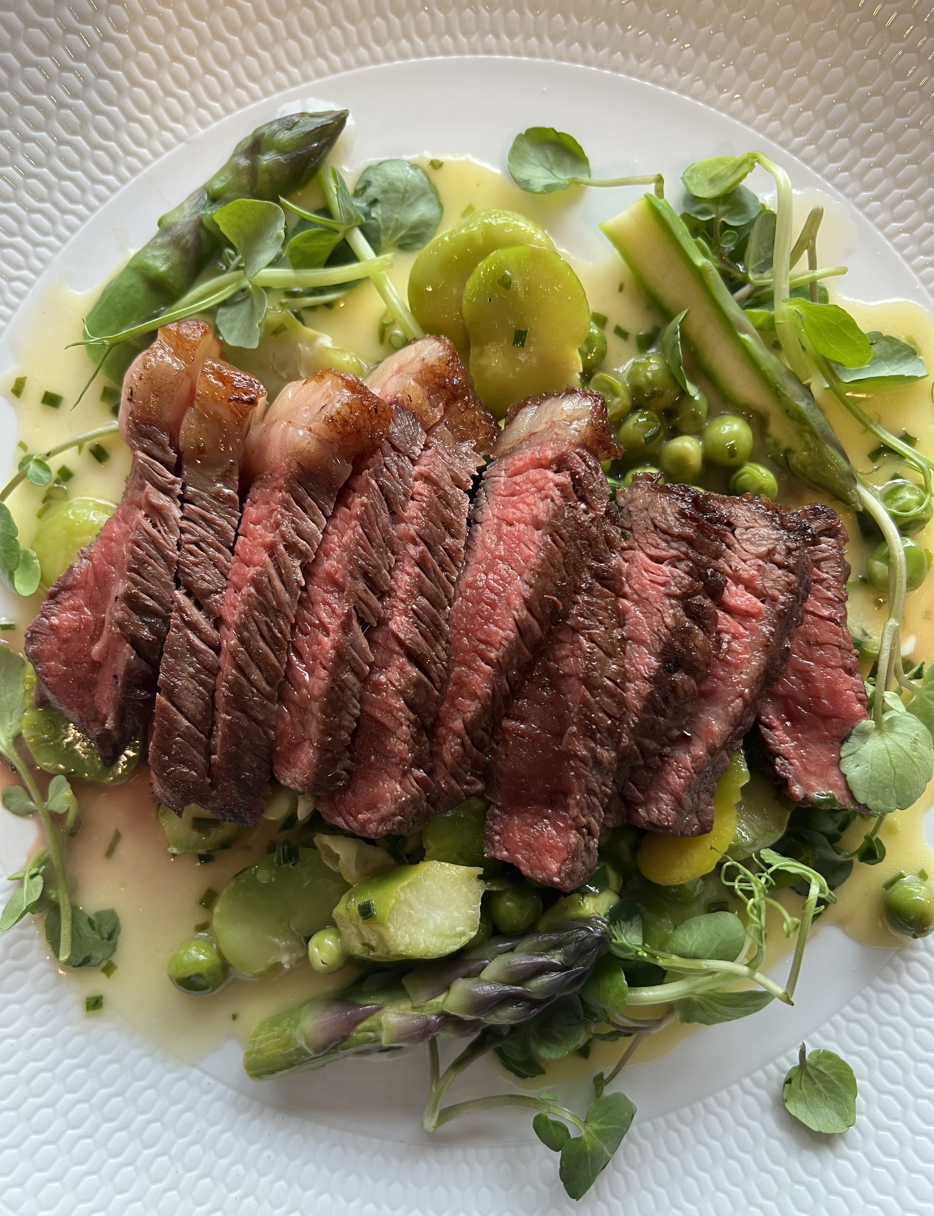 Close up shot of rare sliced steak with asparagus and green spring vegetables