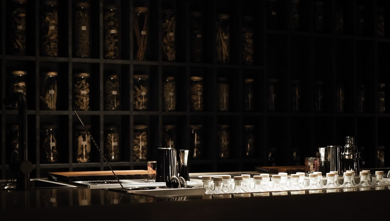 Interior shot of Bar Us in Bangkok with jars of dried herbs and spices behind the bar