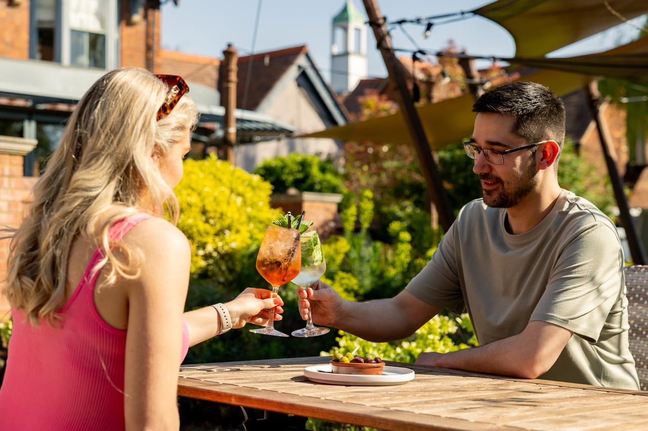 A couple enjoying a drink together in a sunny Wells & Co. beer garden