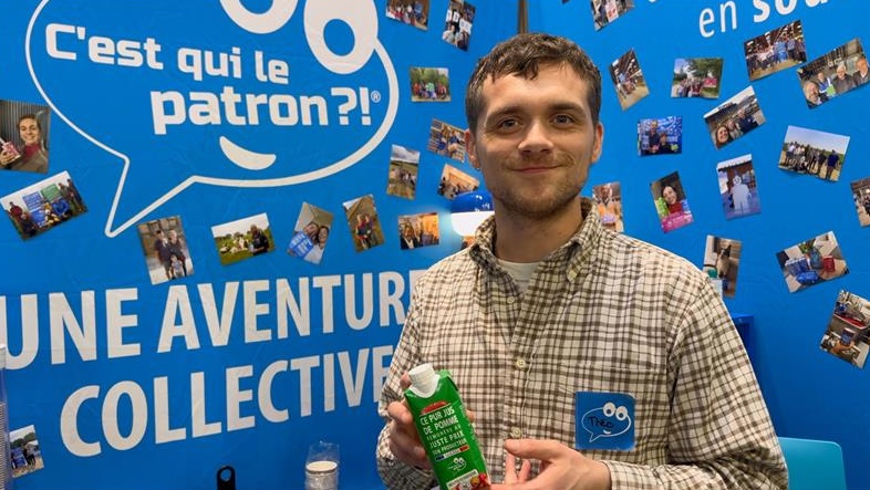 A smiling man in front of a blue backdrop that says "C'est qui le patron?!"